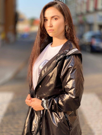 Długa, czarna kurtka parka EGY, zdobiona białym wykończeniem, zapinana na zamek z kapturem, wiązana w pasie.