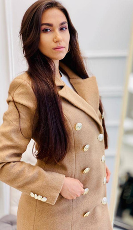 Krótki, elegancki beżowy dwurzędowy płaszcz PRESTIGE la Femme, zapinany na złote guziki.